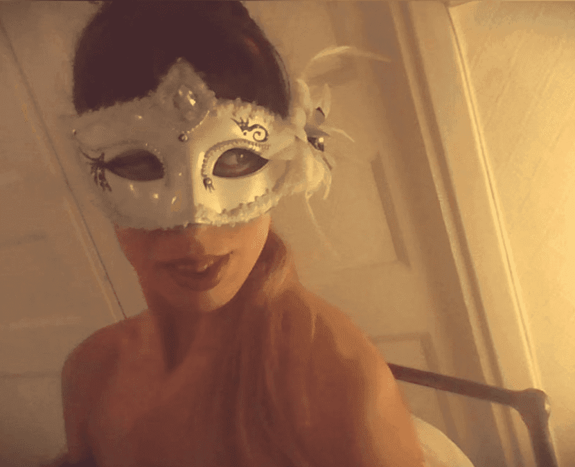 Mathilde-Marie de Malfilâtre, avec un masque de bal masqué blanc orné de perles, de paillettes et de plumes. Avec une ambiance de mystère.