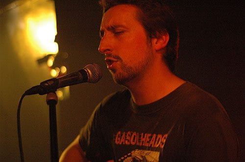 Stéphane Péna dans ses jeunes années en train de chanter au micro avec un air très concentré.