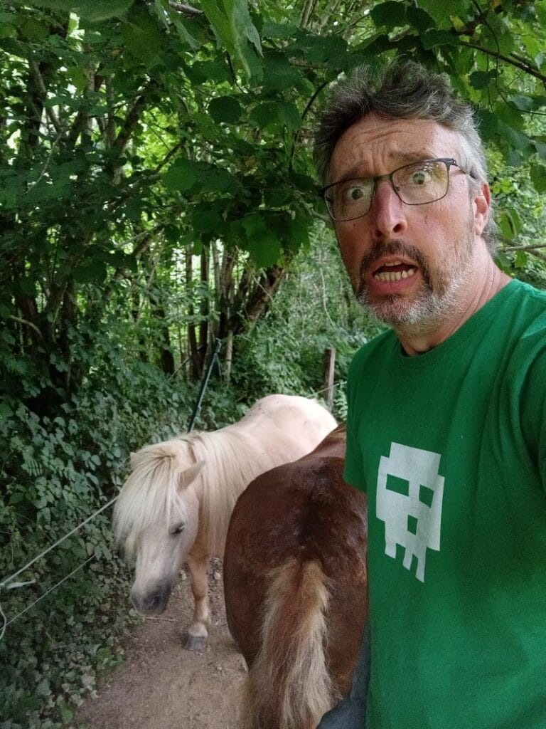 Stéphane Péna, l'air paniqué, avec ses deux poneys, dans la nature.